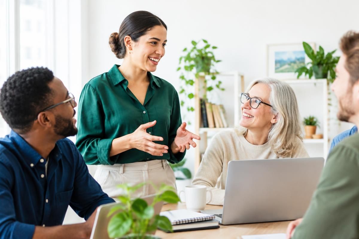 Colleagues of different ages talking around a table in a bright office